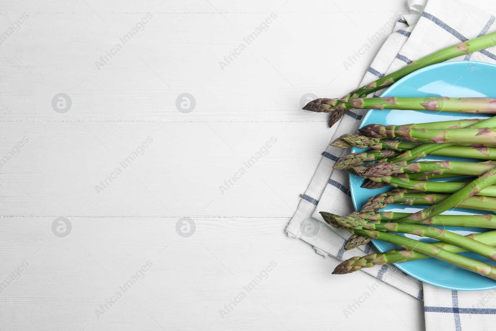 Photo of Fresh raw asparagus on white table, flat lay. Space for text