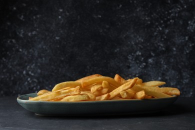 Photo of Plate of tasty french fries on black table
