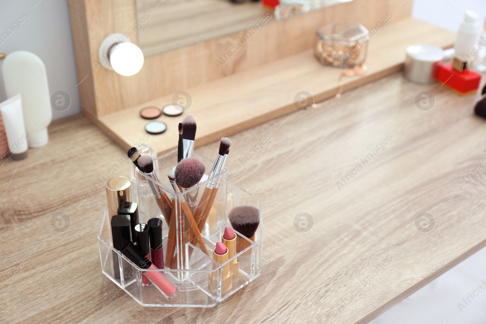 Photo of Organizer with cosmetic products for makeup on table near mirror