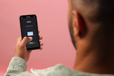 Got new message. Man using smartphone on pink background, closeup