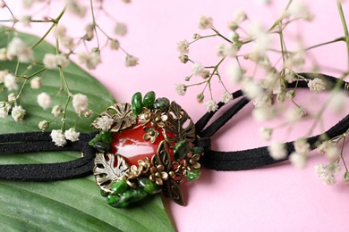 Photo of Beautiful bracelet with cornelian gemstones and flowers on pink background, closeup