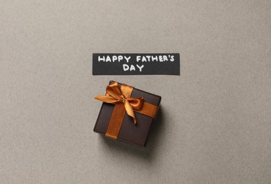 Photo of Card with phrase HAPPY FATHER'S DAY and gift box on light grey background, flat lay