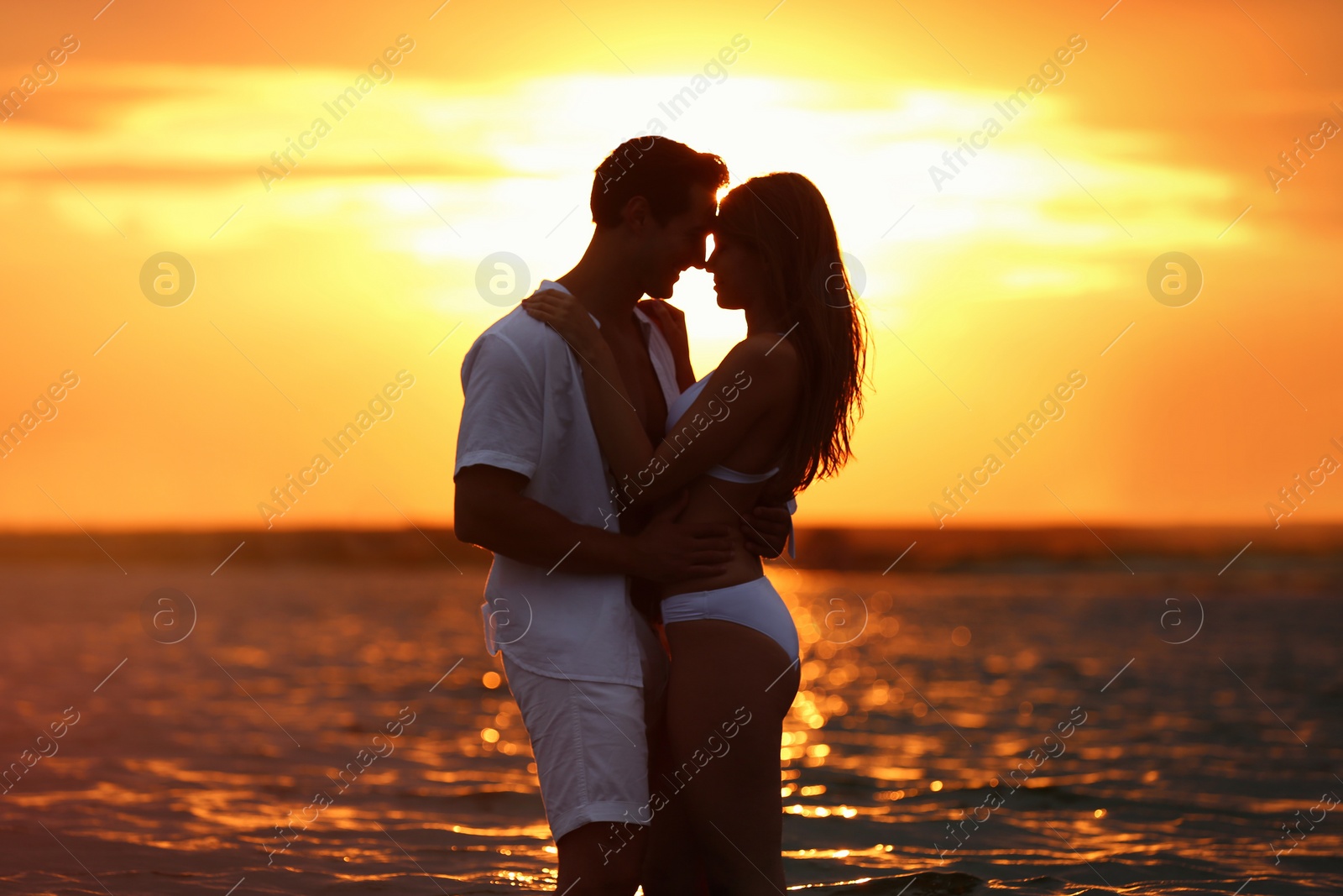 Photo of Happy young couple spending time together on sea beach at sunset