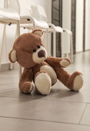 Cute teddy bear left on floor in hallway