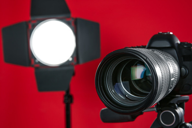 Photo of Professional video camera and lighting equipment on red background, closeup