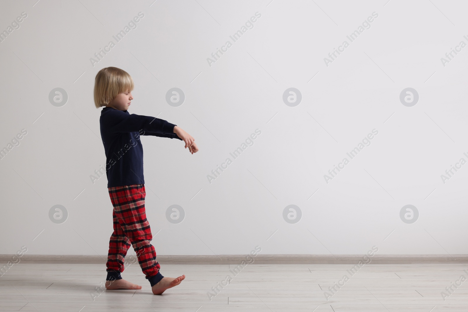 Photo of Boy in pajamas sleepwalking indoors, space for text