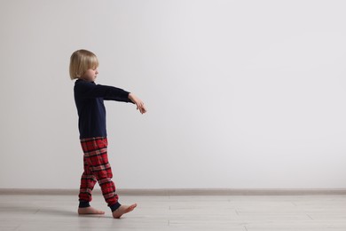 Photo of Boy in pajamas sleepwalking indoors, space for text