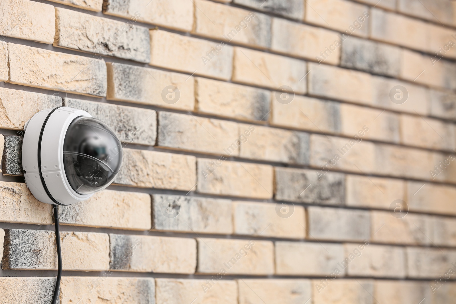 Photo of Modern security CCTV camera on brick wall