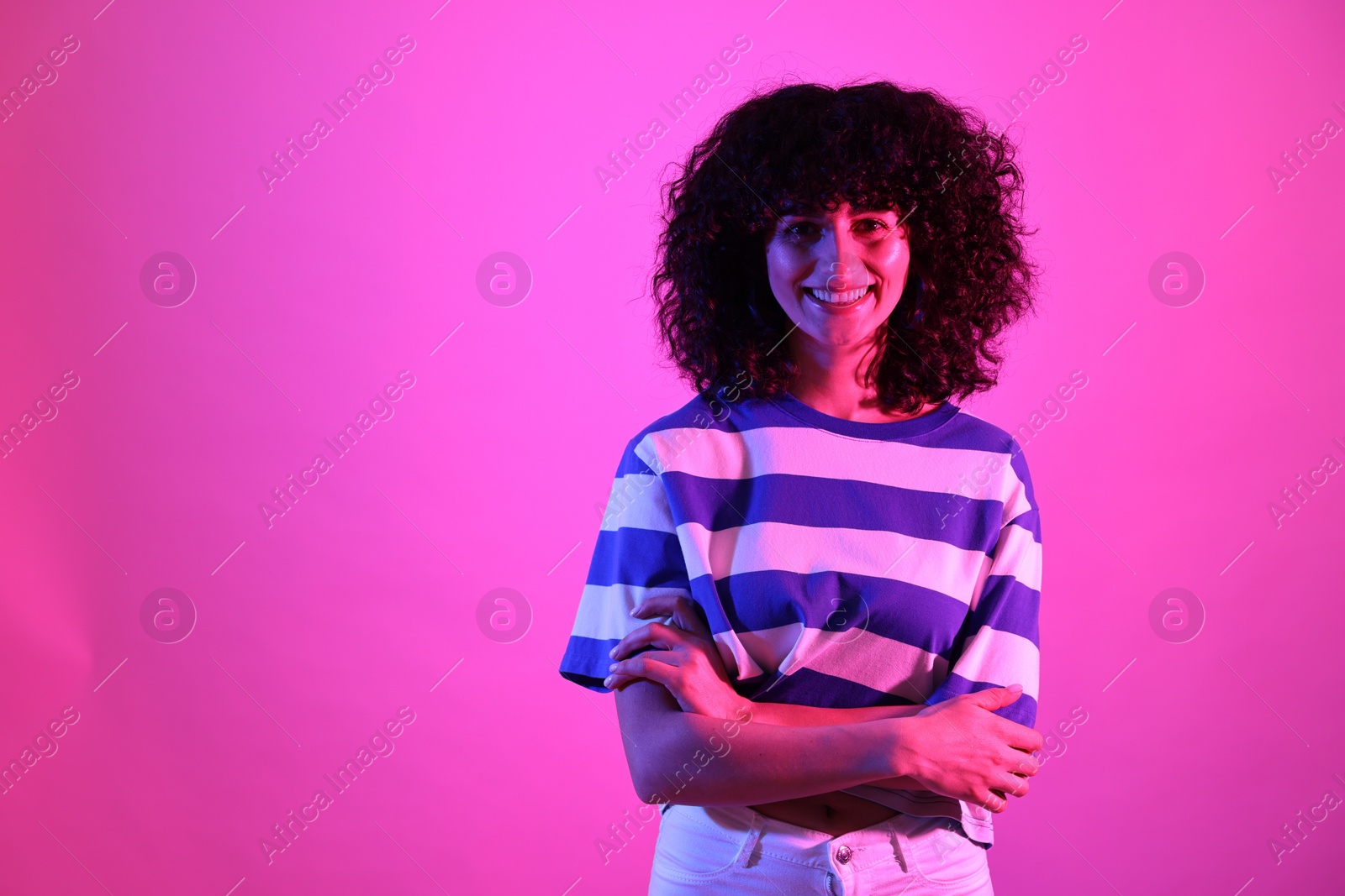 Photo of Beautiful young woman posing on color background in neon lights. Space for text