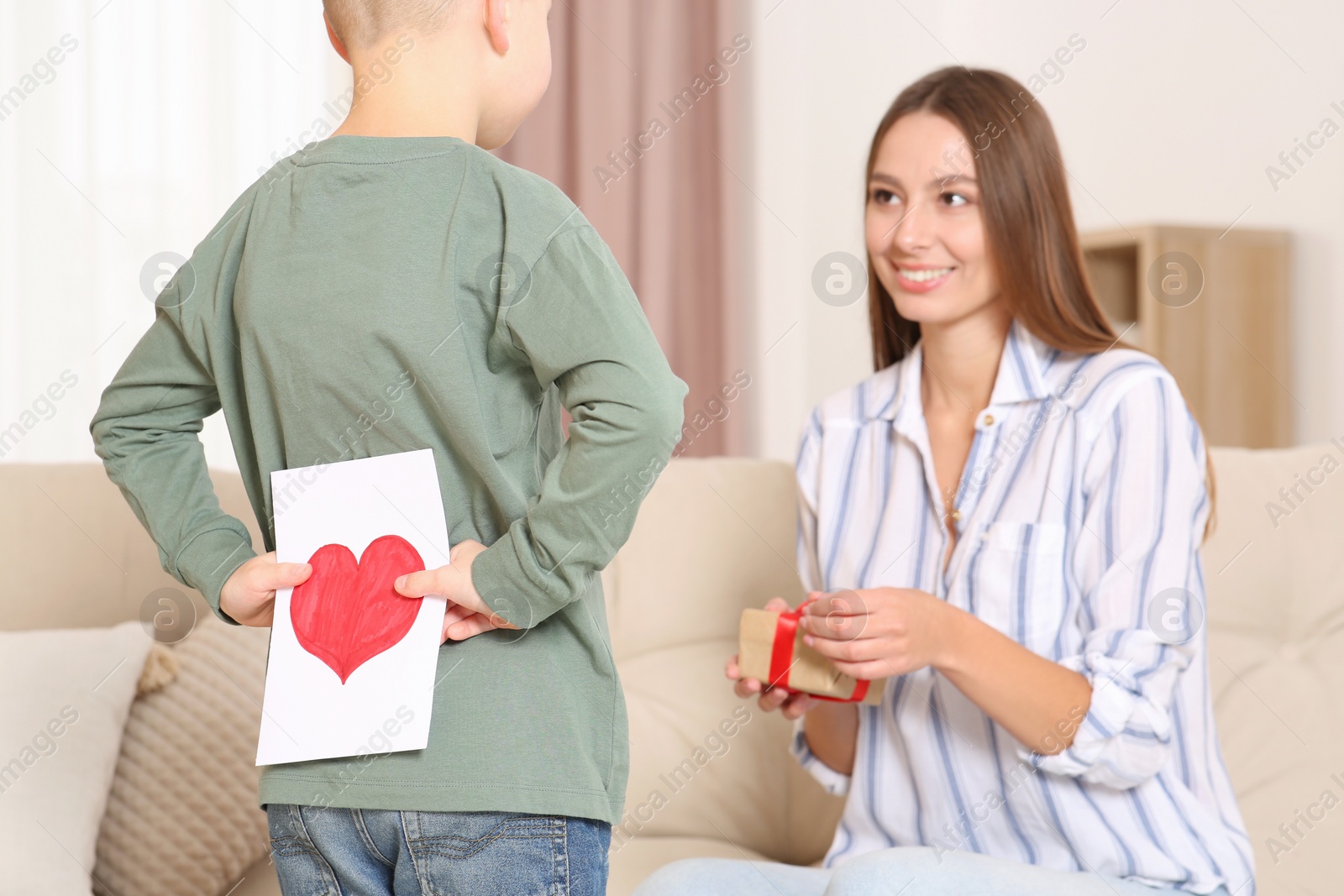 Photo of Little boy presenting gift to his mother at home