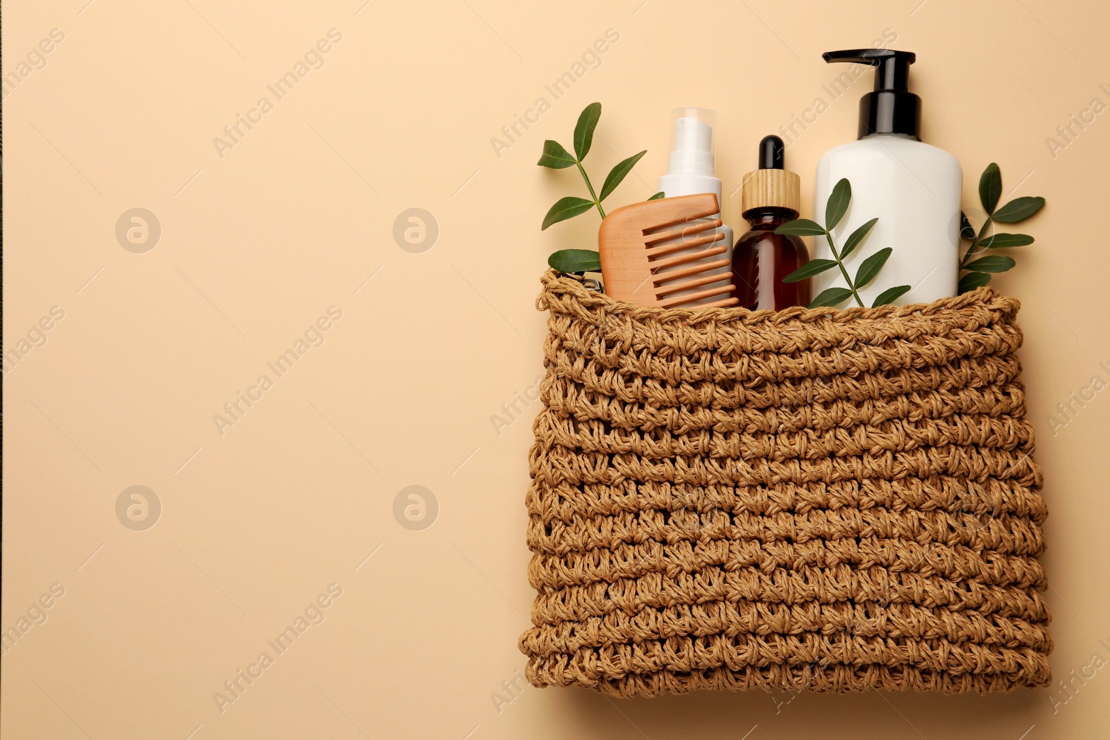 Photo of Preparation for spa. Compact toiletry bag with different cosmetic products on light brown background, flat lay. Space for text