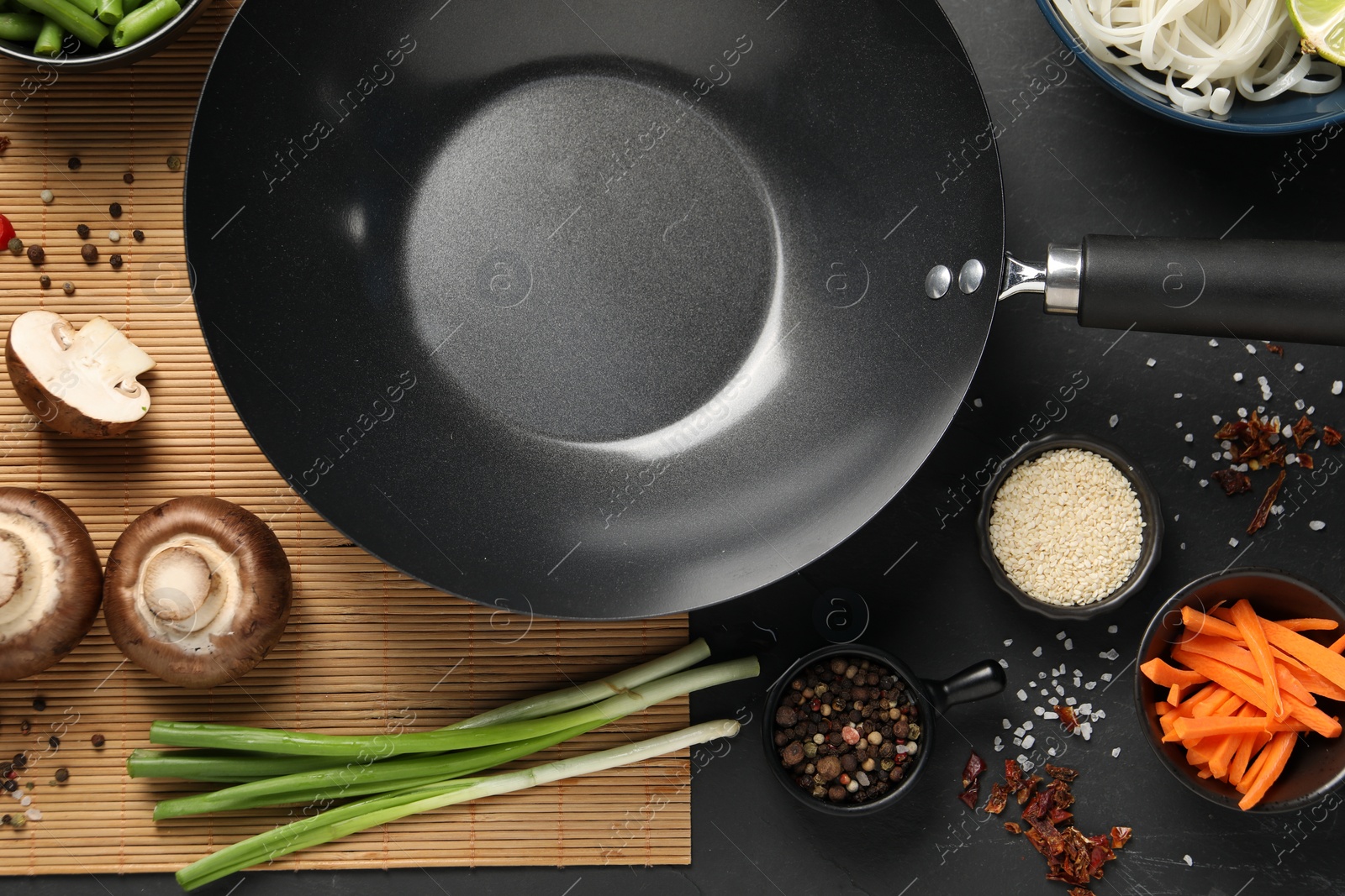 Photo of Flat lay composition with black wok, spices and products on dark table