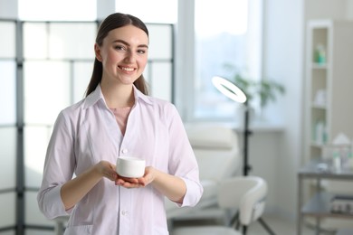 Photo of Cosmetologist with cosmetic product in modern clinic