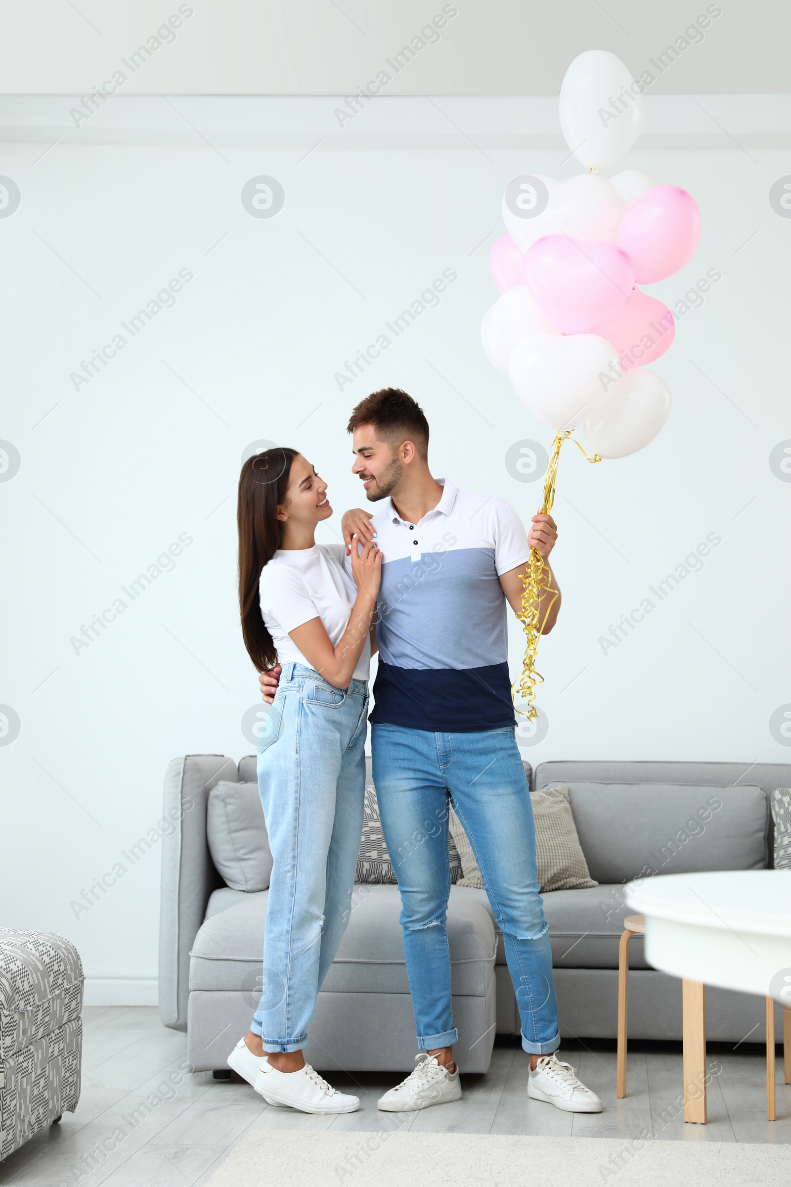 Photo of Young couple with air balloons at home. Celebration of Saint Valentine's Day