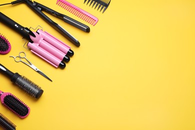 Photo of Flat lay composition of professional hairdresser tools on orange background, space for text