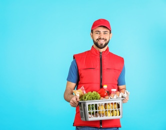 Man holding basket with fresh products on color background, space for text. Food delivery service