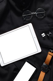 Photo of Modern tablet, smartphone, watch and glasses on black shirt, top view. Space for text