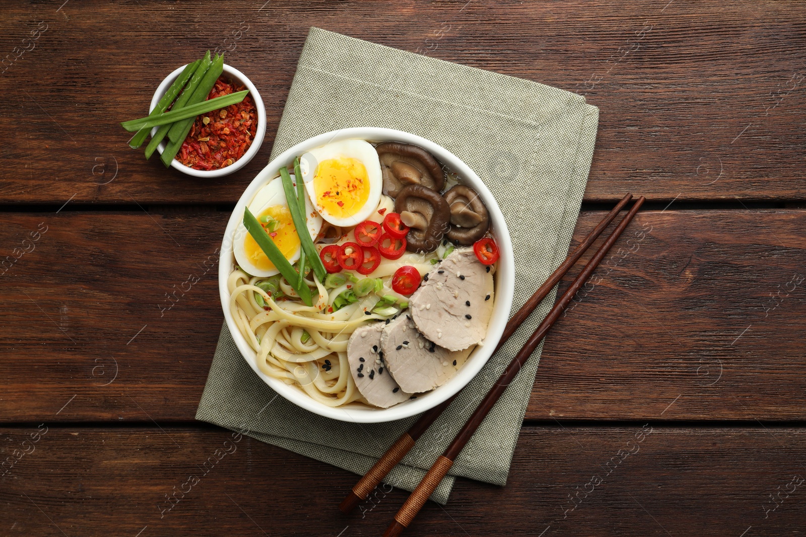 Photo of Delicious ramen with meat in bowl served on wooden table, flat lay. Noodle soup