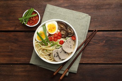 Photo of Delicious ramen with meat in bowl served on wooden table, flat lay. Noodle soup