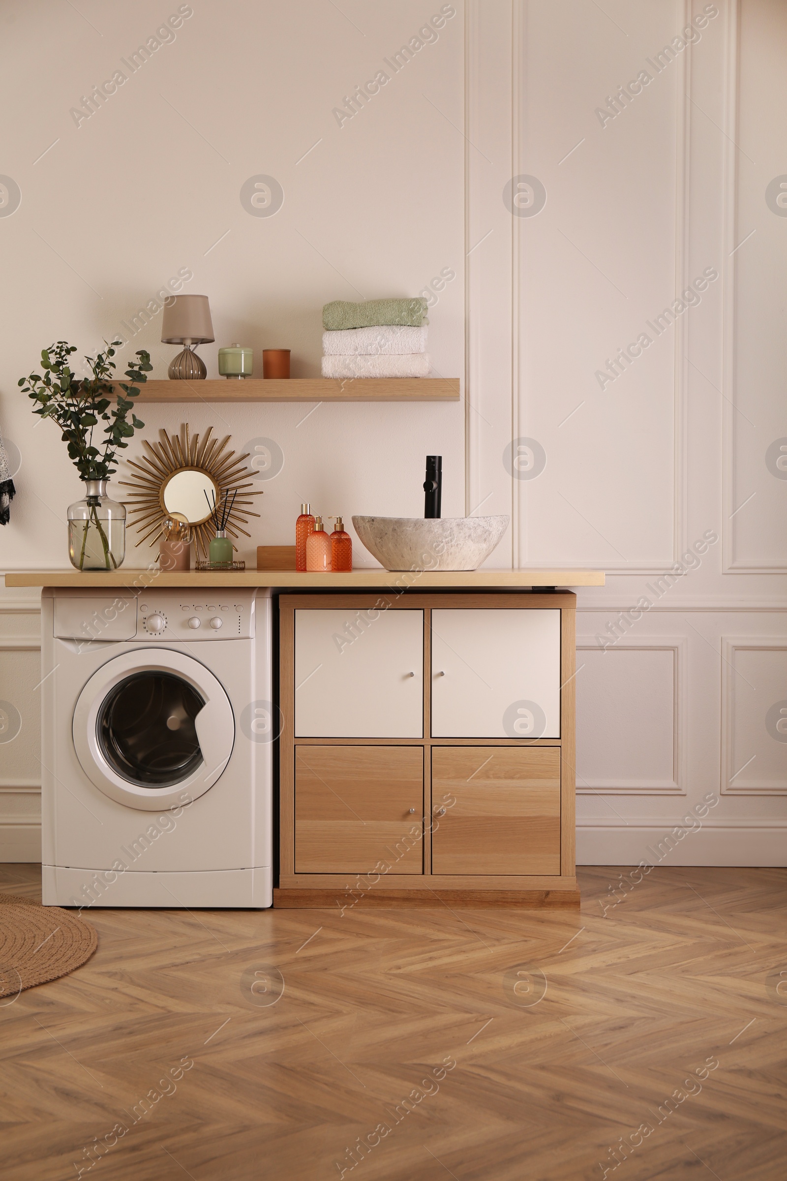 Photo of Laundry room interior with modern washing machine and stylish vessel sink on countertop