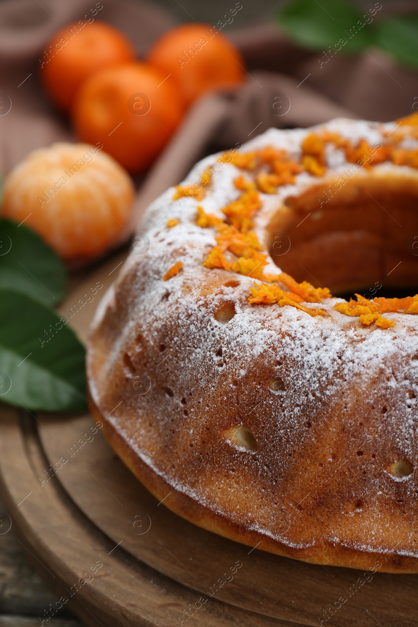 Photo of Homemade yogurt cake with tangerines and powdered sugar on wooden table, closeup