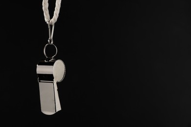 Photo of Referee equipment. Metal whistle on black background, closeup and space for text