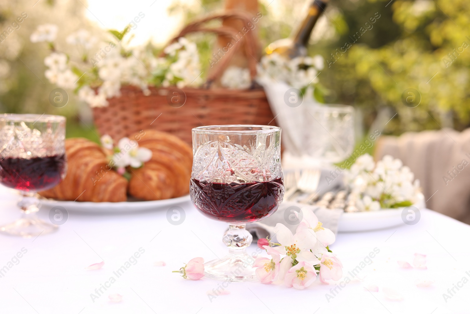 Photo of Stylish table setting with beautiful spring flowers, wine and croissants in garden