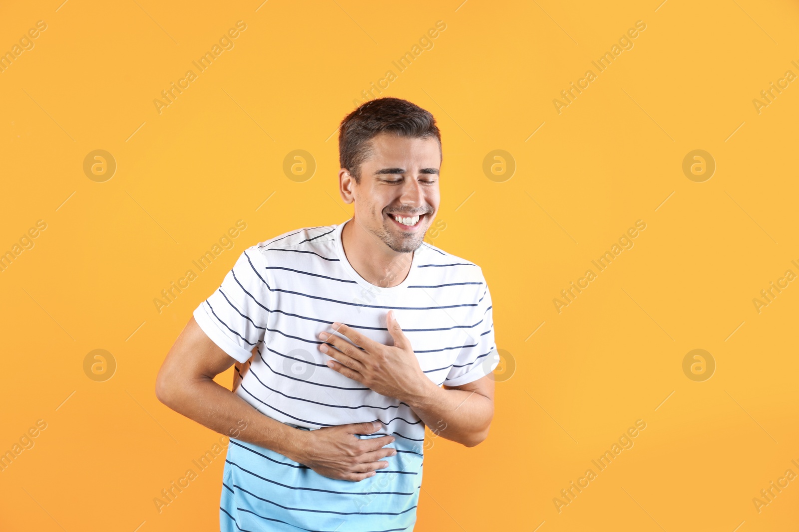 Photo of Portrait of handsome young man laughing on color background