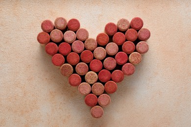 Photo of Heart made of wine bottle corks on textured table, top view