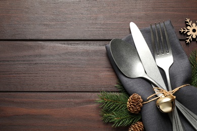 Photo of Cutlery set and festive decor on wooden table, flat lay with space for text. Christmas celebration