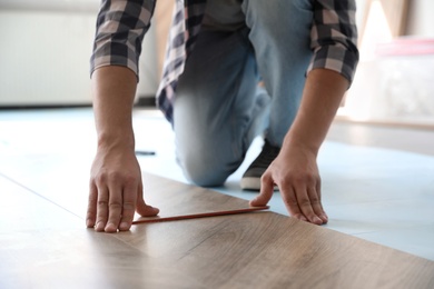 Worker installing laminated wooden floor indoors, closeup