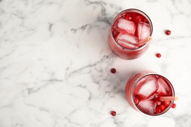 Photo of Tasty refreshing cranberry cocktails on white marble table, flat lay. Space for text