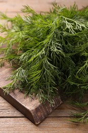 Photo of Board with sprigs of fresh dill on wooden table, closeup