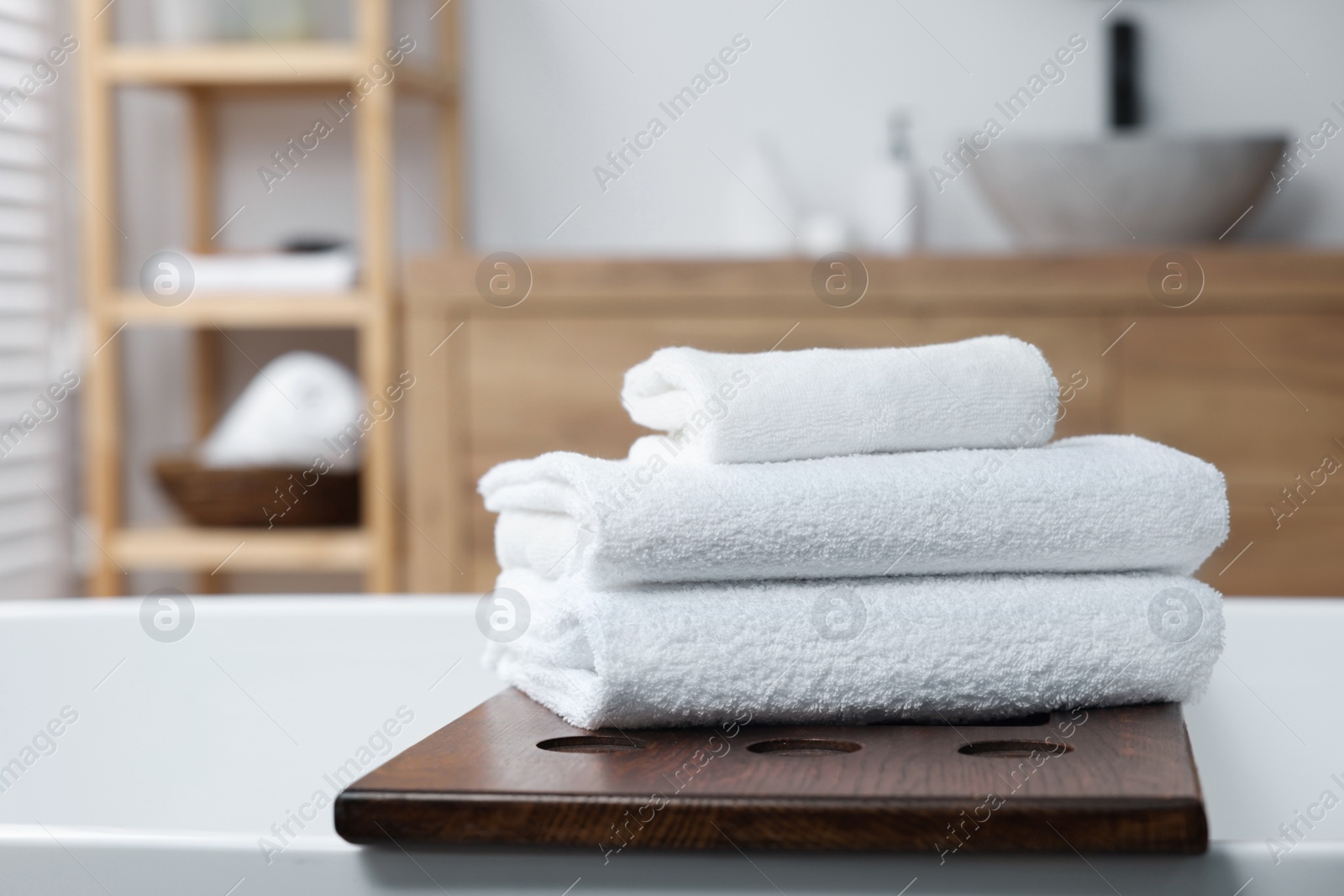 Photo of Stacked bath towels on tub tray in bathroom