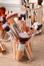 Set of professional makeup brushes on wooden table