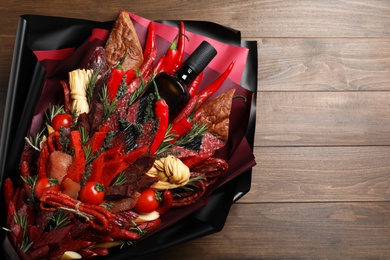 Beautiful edible bouquet with meat, cheese and vegetables on wooden table, top view. Space for text