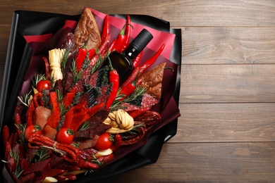 Photo of Beautiful edible bouquet with meat, cheese and vegetables on wooden table, top view. Space for text