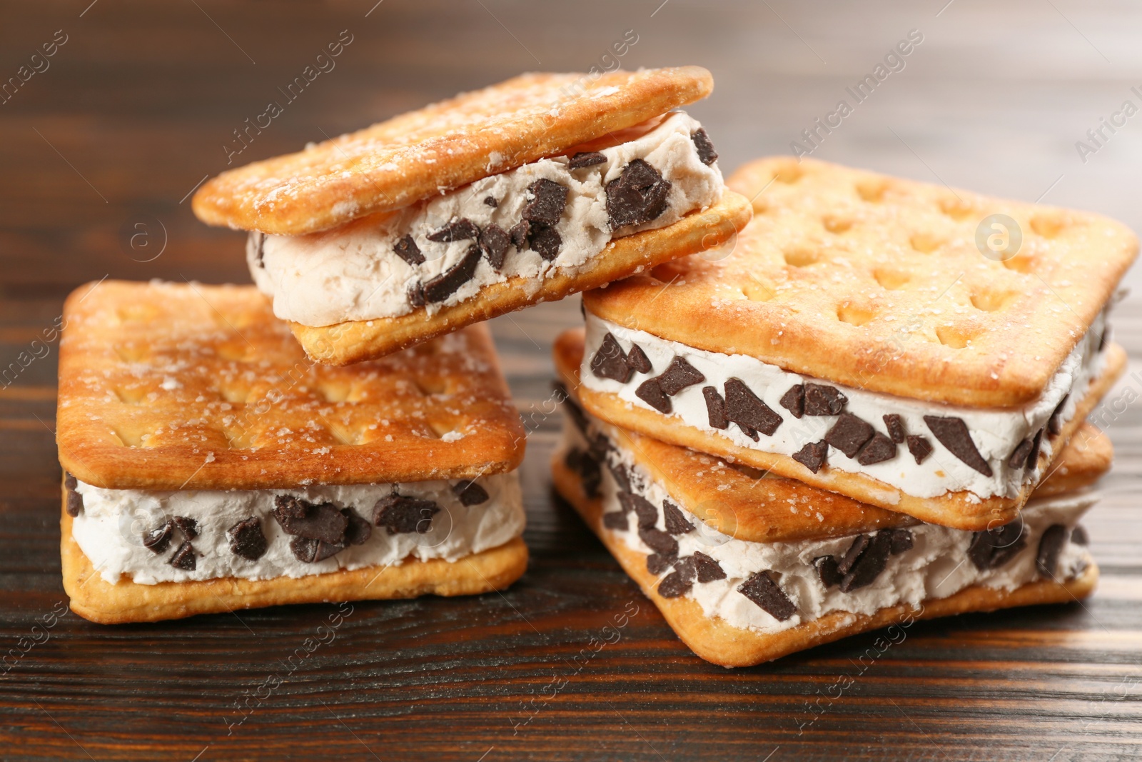 Photo of Sweet delicious ice cream cookie sandwiches on wooden table, closeup