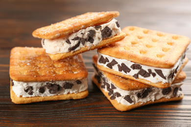 Photo of Sweet delicious ice cream cookie sandwiches on wooden table, closeup