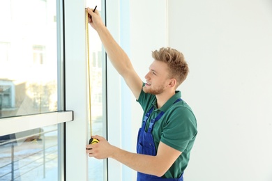 Photo of Service man measuring window for installation indoors