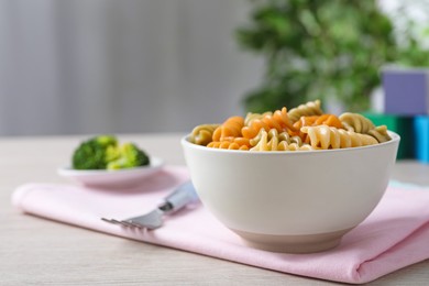 Bowl with tasty fusilli pasta on wooden table indoors. Space for text