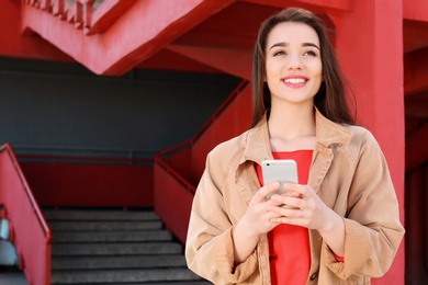 Photo of Young woman using mobile phone outdoors