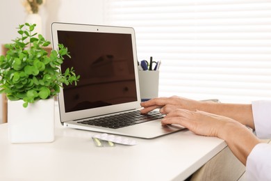 Photo of Doctor working on laptop at desk in clinic, closeup. Online medicine concept