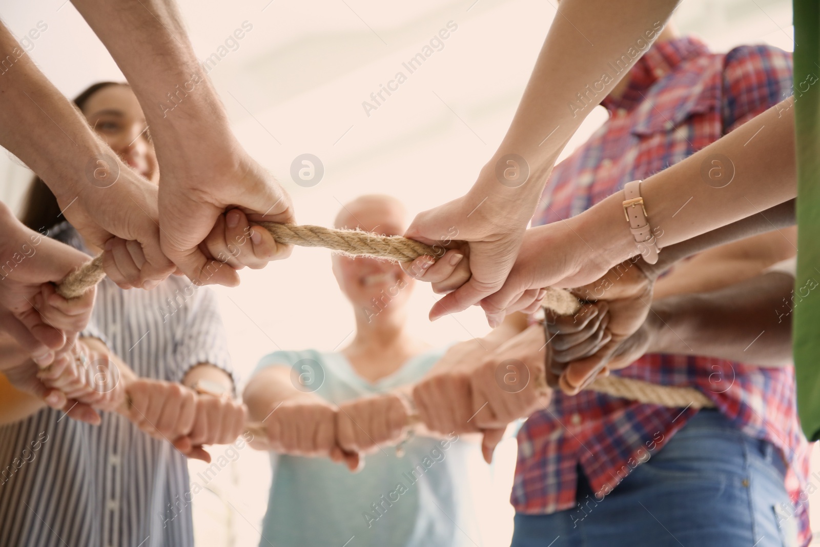 Photo of People holding rope together on light background, closeup of hands. Unity concept