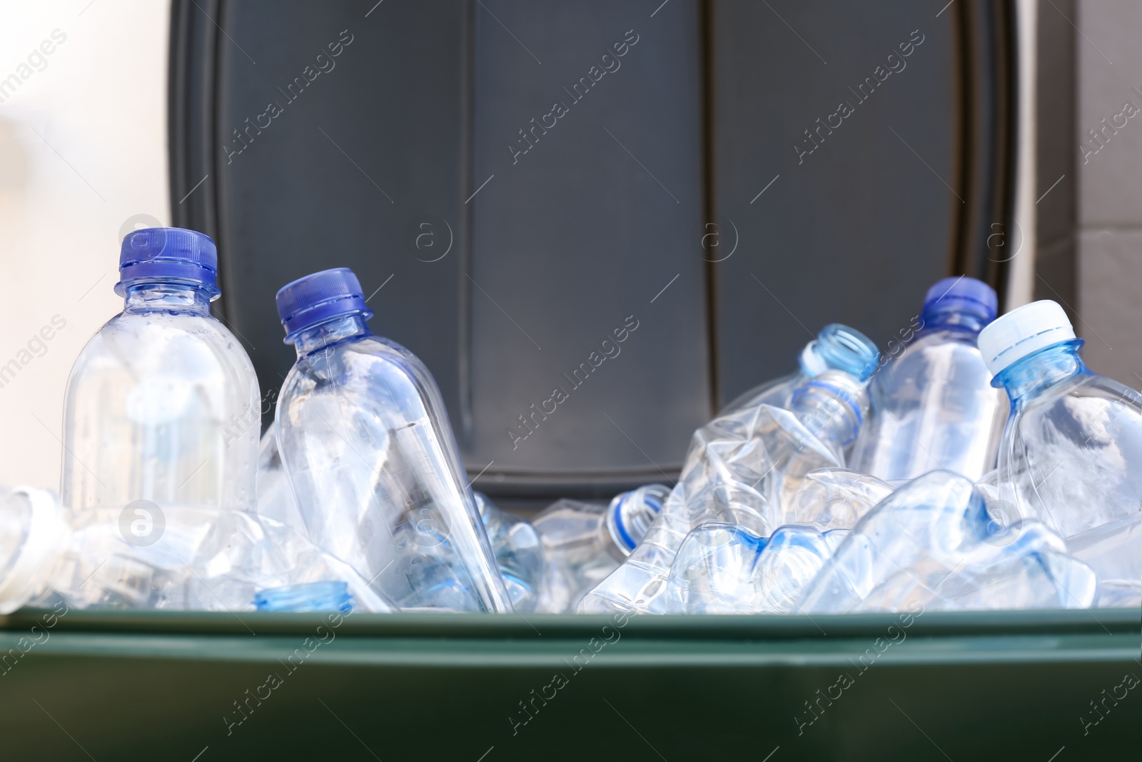 Photo of Many used plastic bottles in trash bin, closeup. Recycling problem