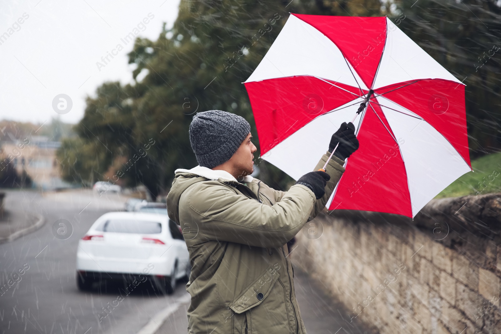 Photo of Man with colorful umbrella caught in gust of wind on street