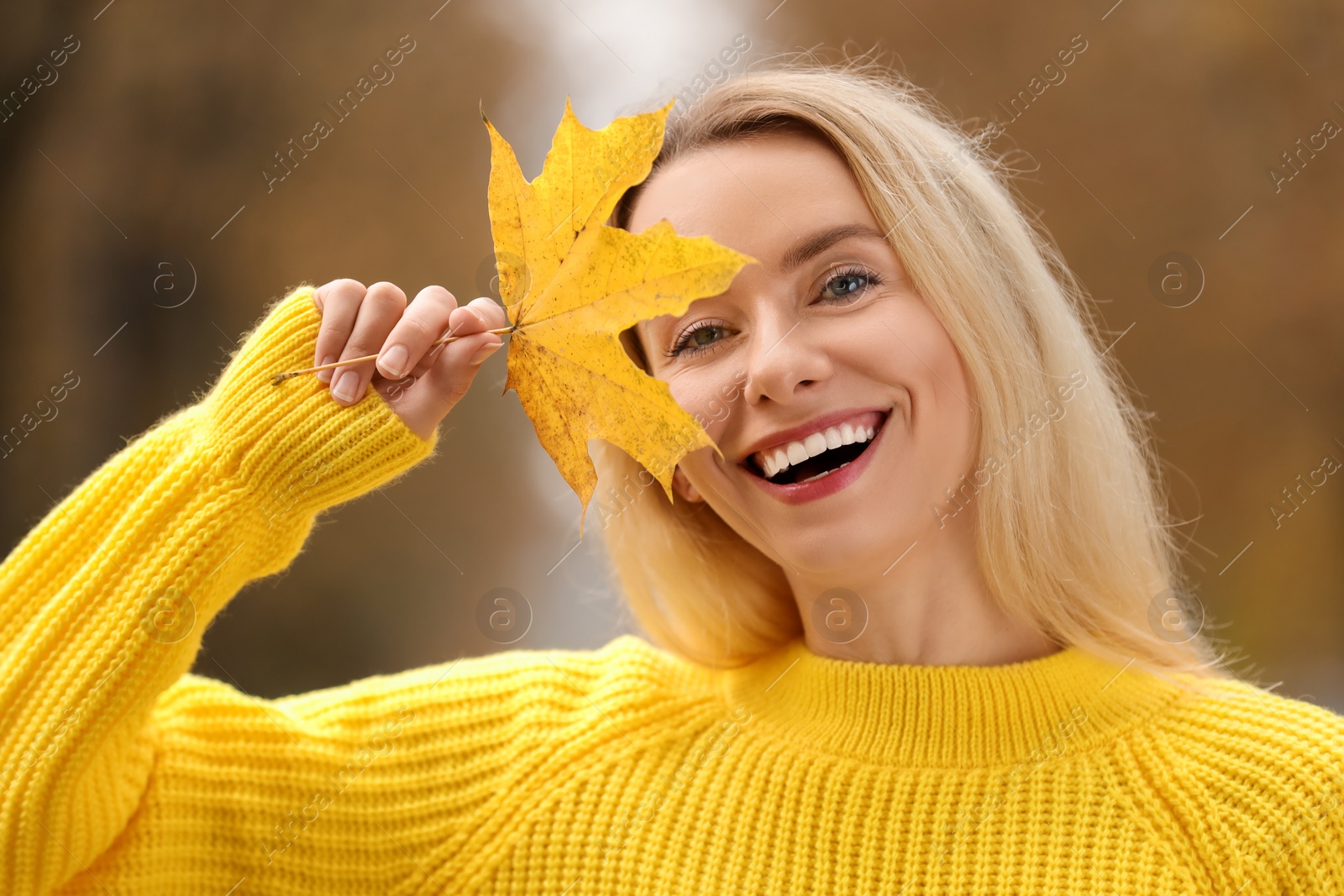 Photo of Portrait of happy woman with autumn leaf outdoors