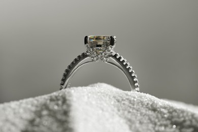Photo of Luxury jewelry. Stylish presentation of ring in sand against grey background, closeup
