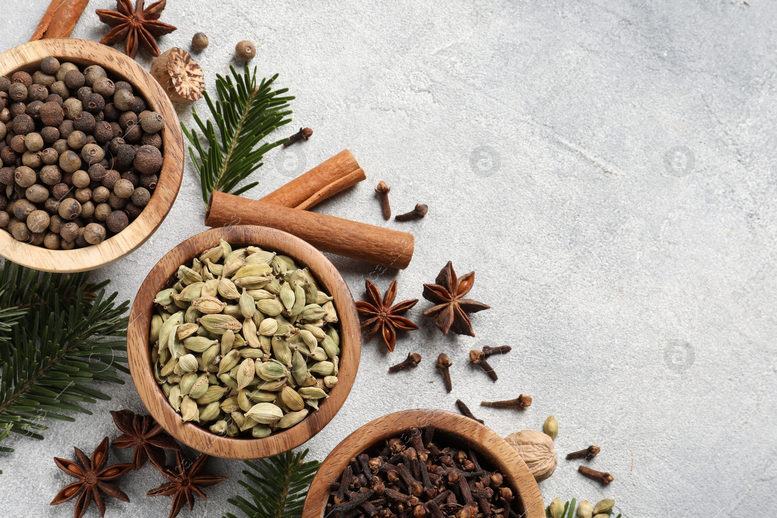 Photo of Different aromatic spices and fir branches on light textured table, flat lay. Space for text