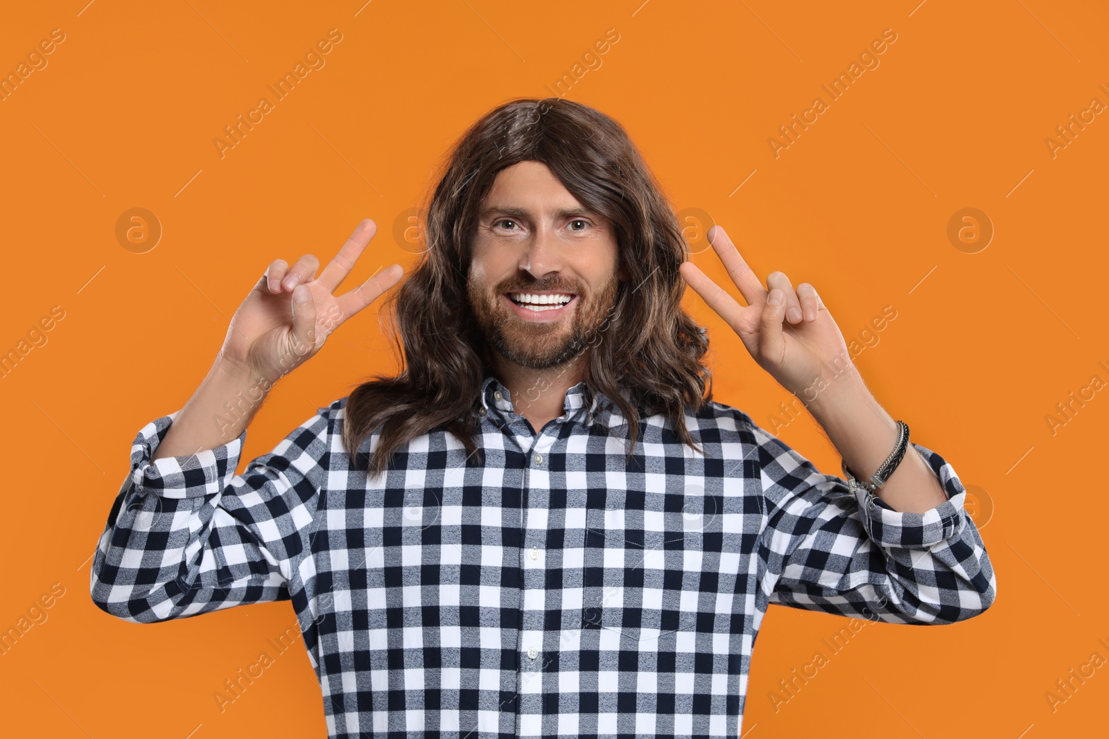 Photo of Hippie man showing V-sign on orange background